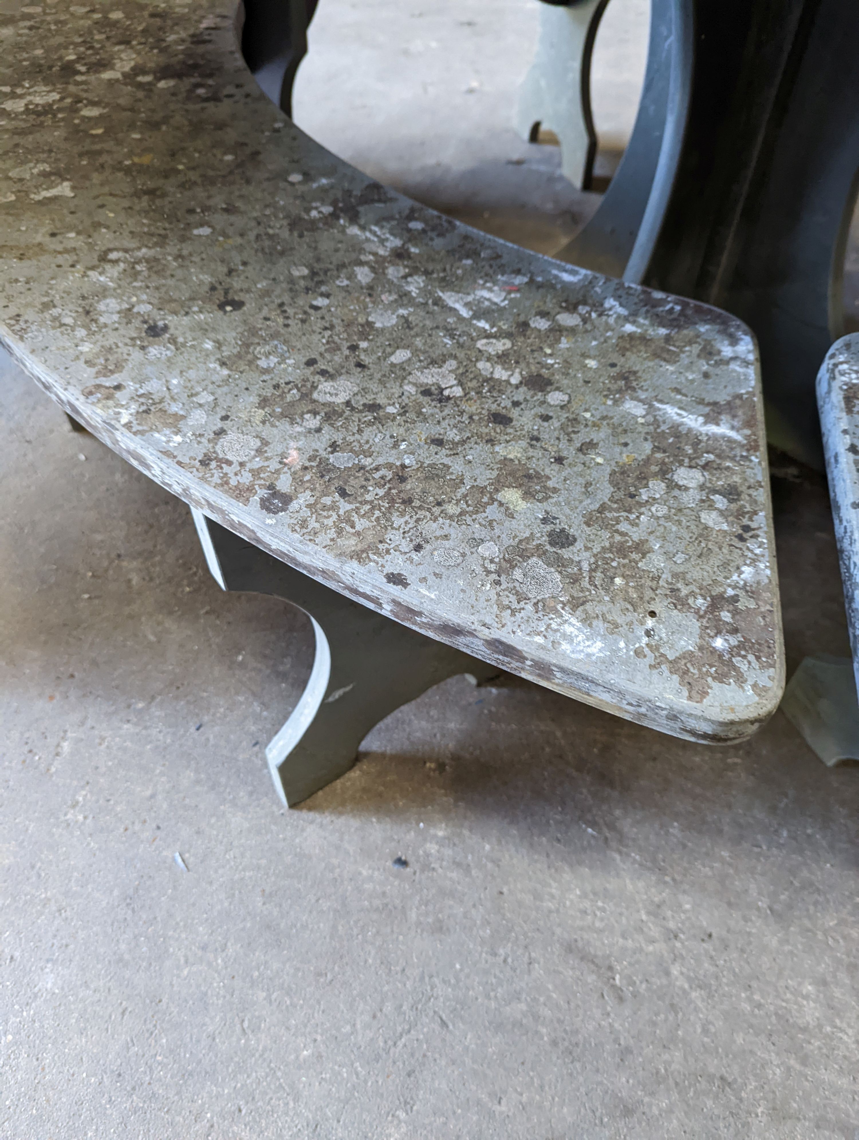 A heavy slate circular topped garden table, diameter 125cm, height 79cm together with four crescent shaped slate garden benches